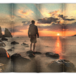 Hajtogatott kép 01 - Naplementés tengerparton egy férfi áll egy tengerből kiemelkedő alacsony sziklán.