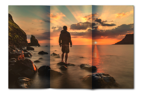 Hajtogatott kép 21 - Naplementés tengerparton egy férfi áll egy tengerből kiemelkedő alacsony sziklán.
